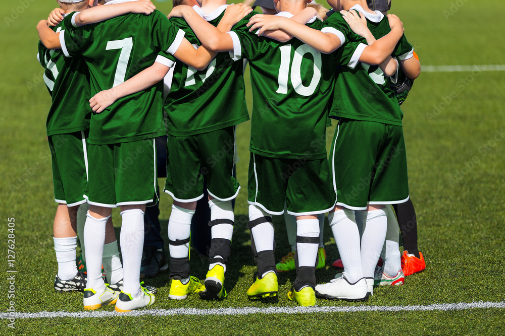 Fototapeta premium Sports team standing together on field. Football team motivated by coach. Youth soccer match