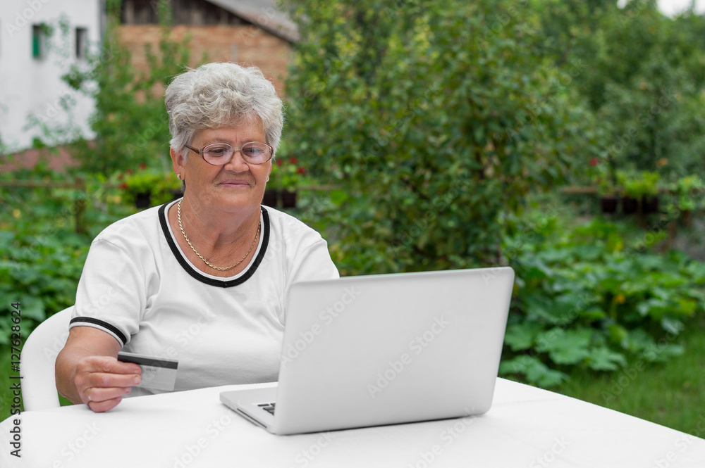 Elderly lady makes a purchase through the Internet with a credit Elderly lady makes a purchase through the Internet with a credit