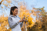 Girl typing text message on smart phone in park. Image of young