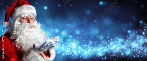 Santa Claus Blowing Magic Christmas Stars In Snowy Night
 photo