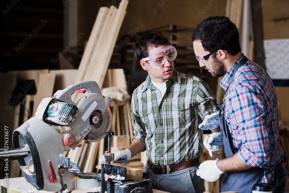 Two men builder with circular saw having a conversation Two men builder with circular saw having a conversation