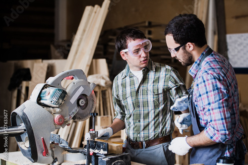 Two men builder with circular saw having a conversation