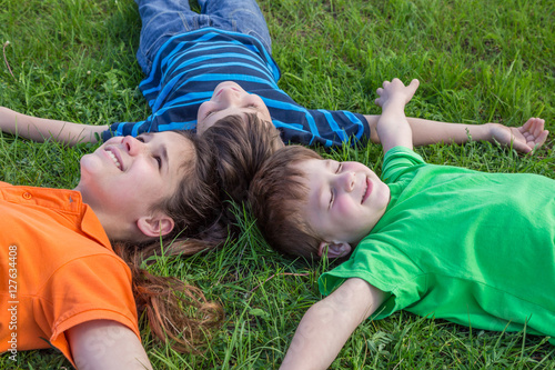 Three dreaming kids lying down on green grass