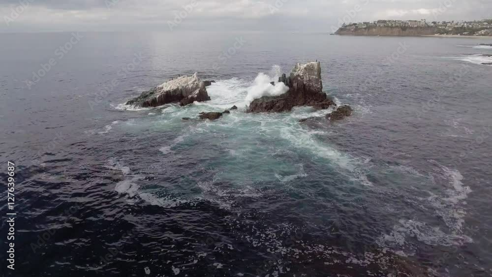 Waves crashing over an exposed set of large rocks in the pacific ocean just off the shore from Crescent Bay in Laguna Beach, California. Waves crashing over an exposed set of large rocks in the pacific ocean just off the shore from Crescent Bay in Laguna Beach, California.
