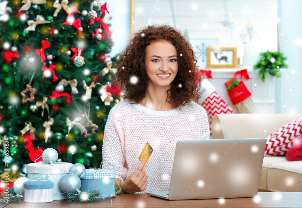 Young woman shopping online with credit card at home for Christmas. Snowy effect. Christmas shopping concept. Young woman shopping online with credit card at home for Christmas. Snowy effect. Christmas shopping concept.