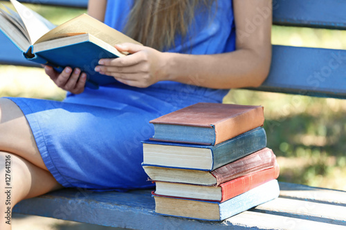 Woman reading book and sitting on a bench