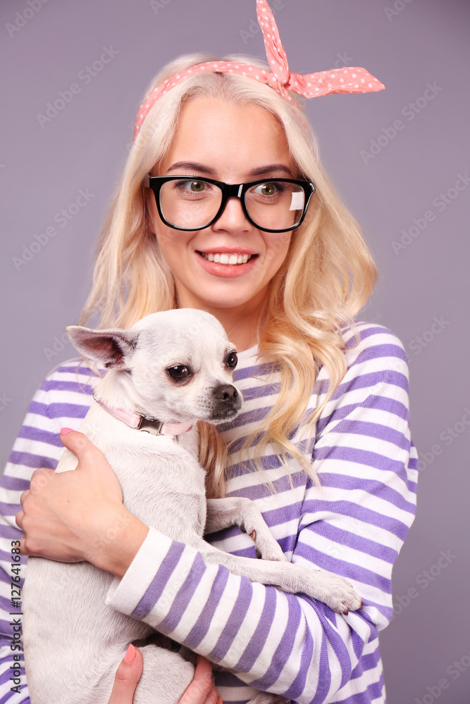 Beautiful girl holding cute dog on grey background Beautiful girl holding cute dog on grey background