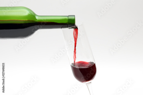 red wine from the green bottle is poured into a glass