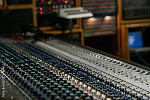 Vintage sound or audio mixer in a recording studio. Knobs, dials and sliders on a soundboard. © studiolaska