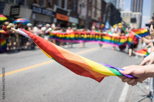 People participating in the World Pride Parade in Toronto. Spectators can be seen beside the path holding a rainbow flag. LGBTQ
