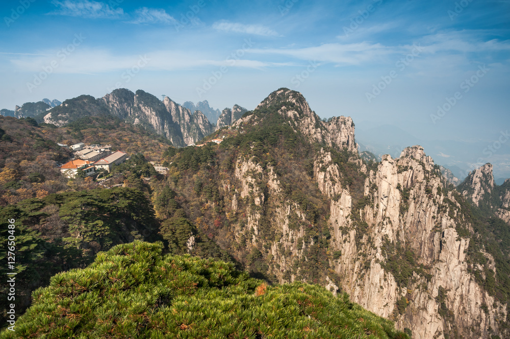 Pine trees on cliff edge, Huangshan Mountain Range in China. Anhui Province - Scenic landscape with steep cliffs and trees during a sunny day.