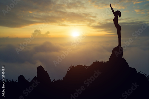 Silhouette young woman practicing yoga on the muontain at sunset