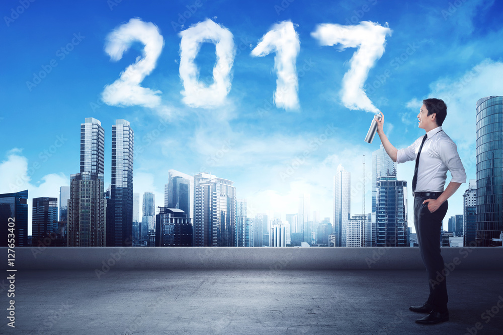 Business man spraying white 2017 year cloud shape Business man spraying white 2017 year cloud shape