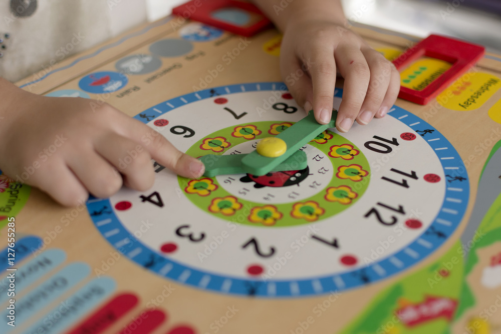 Little kid learning time with clock toy of Montessori. StockFoto