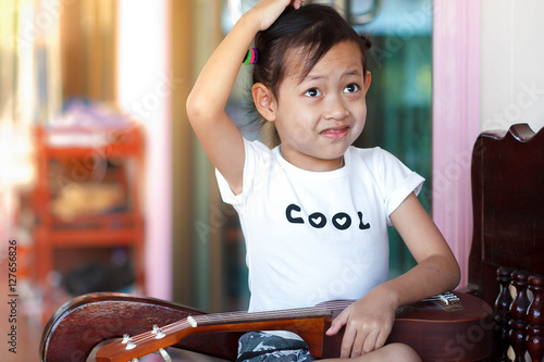 Happy child girl playing akulele at home.Selective Focus photo