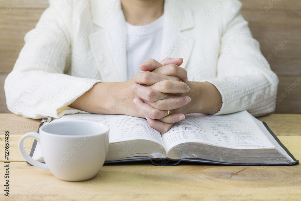 woman pray on holy bible with a cup of coffee on wooden table woman pray on holy bible with a cup of coffee on wooden table