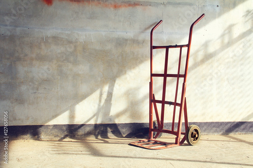 Red empty sack barrow or hand truck dolly  Beside old walls back photo