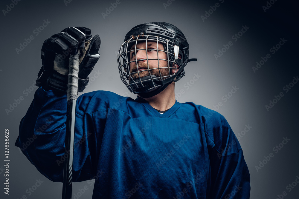 A bearded ice-hockey player in safety helmet holds the gaming st