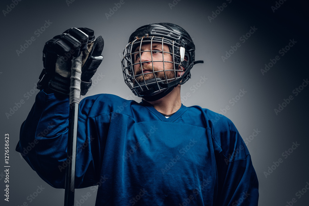 Fototapeta premium A bearded ice-hockey player in safety helmet holds the gaming st
