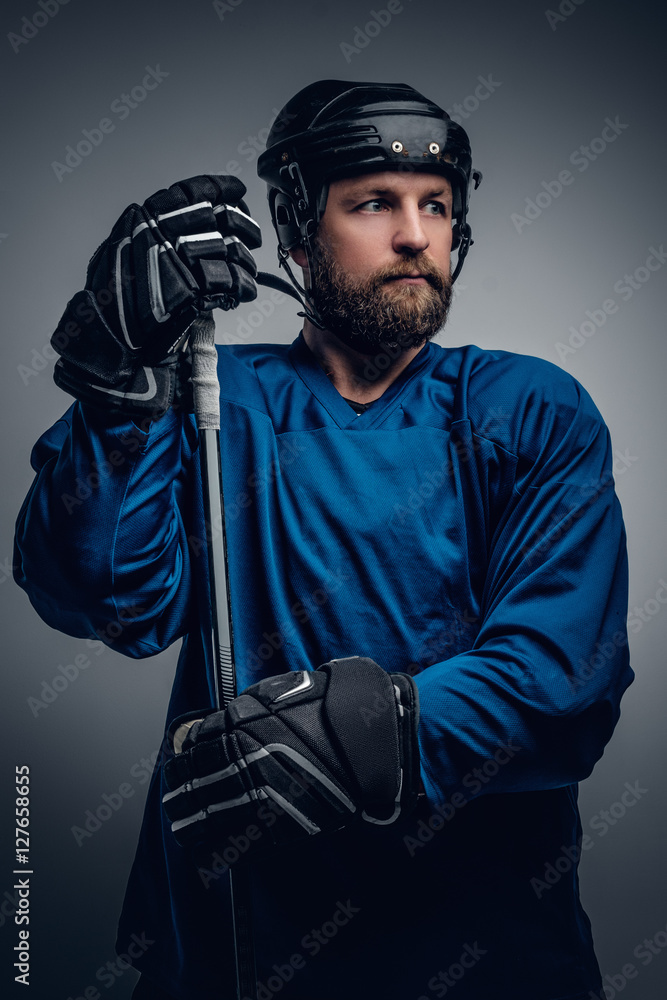 Fototapeta premium Bearded ice-hockey player in safety helmet holds the gaming stic
