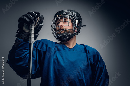 A bearded ice-hockey player in safety helmet holds the gaming st