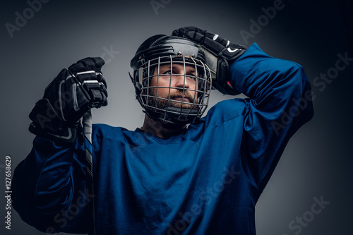 Photography A bearded ice-hockey player in safety helmet holds the gaming st