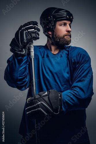 Bearded ice-hockey player in safety helmet holds the gaming stic