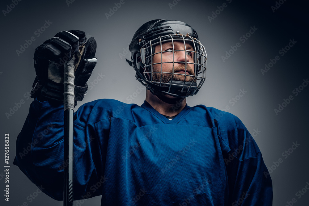 Bearded ice-hockey player in safety helmet holds the gaming stic