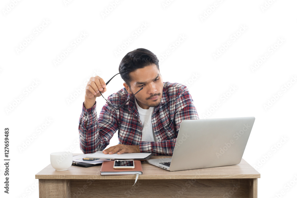 Thoughtful young man holding glasses looking at laptop while sit Thoughtful young man holding glasses looking at laptop while sit
