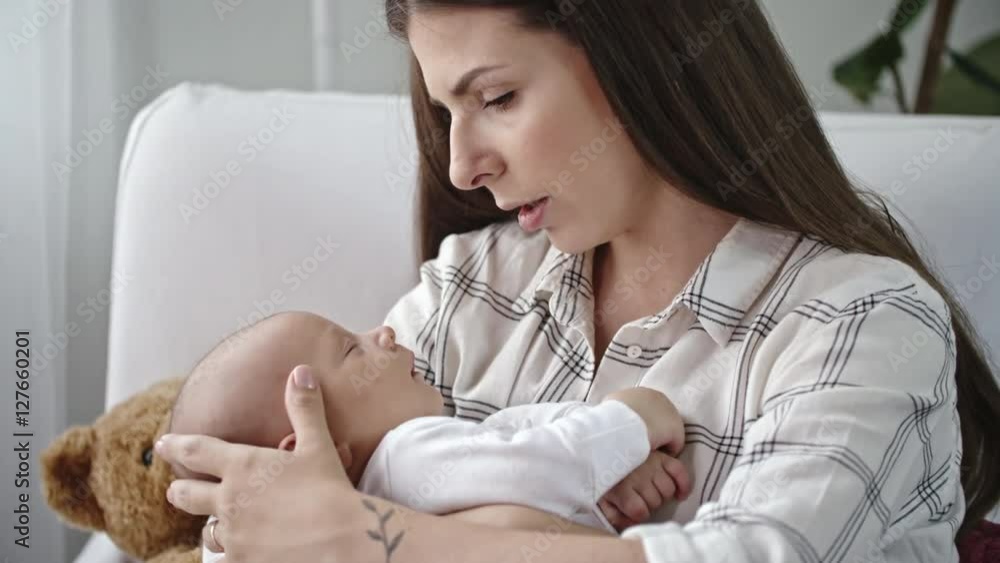 Lockdown of beautiful young mother looking with tenderness at her sleeping infant boy and caressing his head Lockdown of beautiful young mother looking with tenderness at her sleeping infant boy and caressing his head