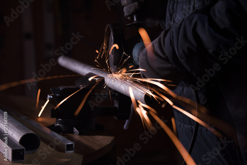 Εκτύπωση καμβά worker sawing metal pipe with a electric rotary angle grinder on an working tabl