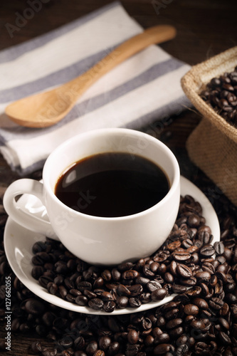 warm cup of coffee with sack inside by coffee bean on wood background