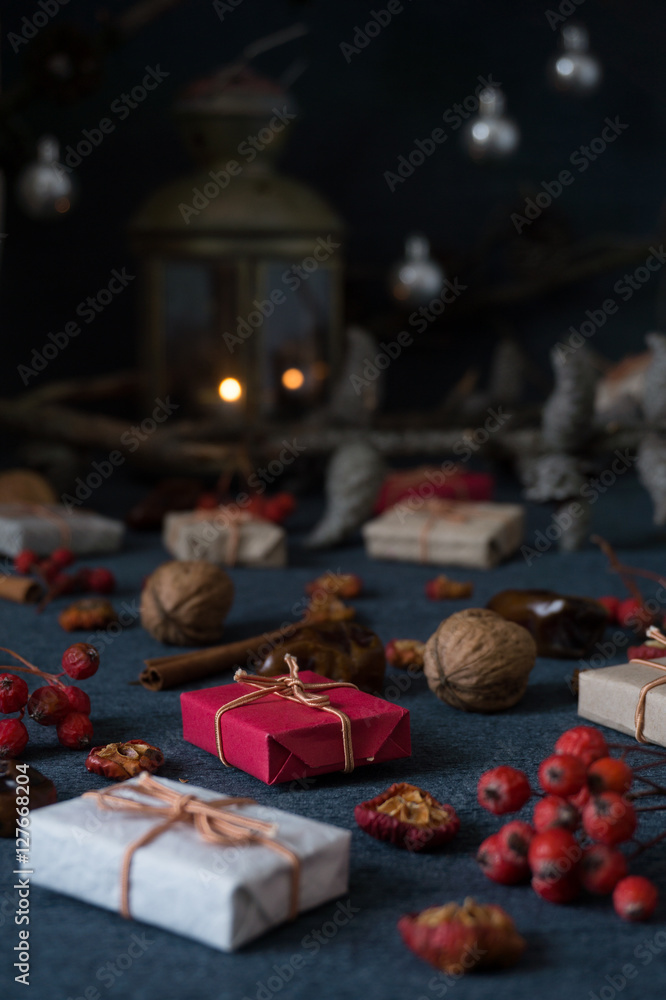 Christmas gifts, rowan, nuts, old lamp on dark surface