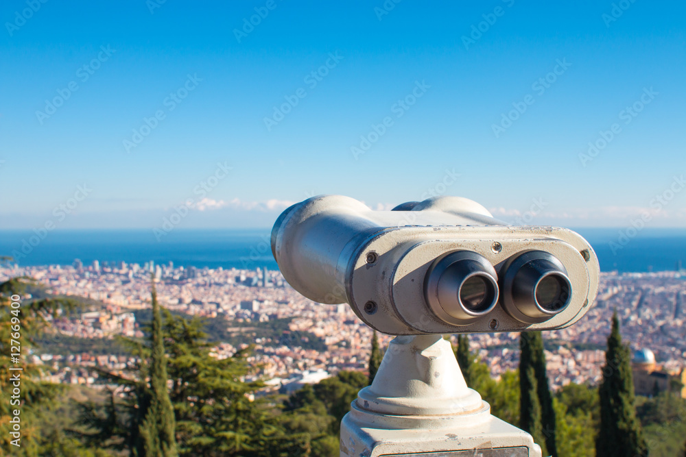 Coin operated binoculars and panoramic view of the city on a sunny day