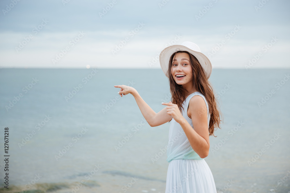Happy lovely young woman smiling and pointing away on beach Happy lovely young woman smiling and pointing away on beach