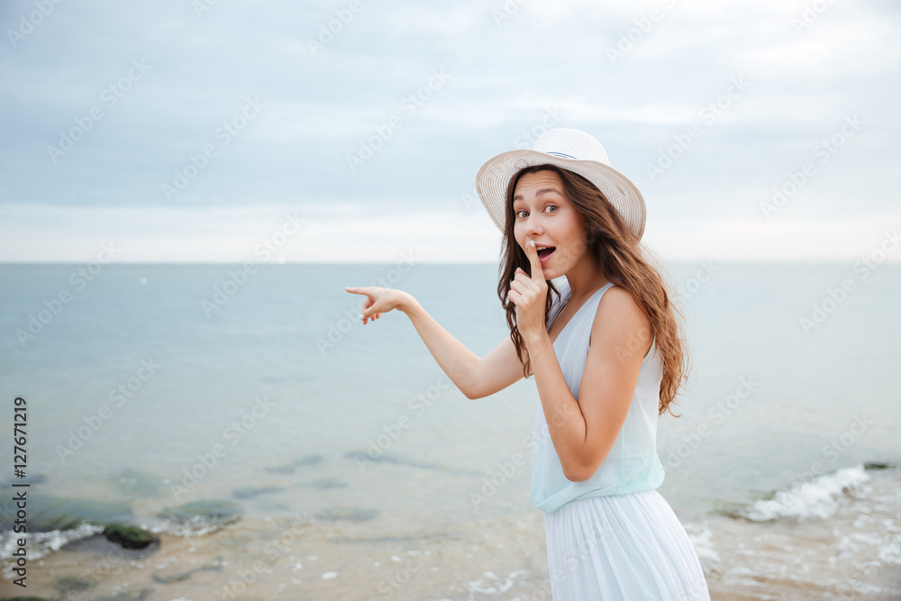Woman showing silence sign and pointing at the sea Woman showing silence sign and pointing at the sea