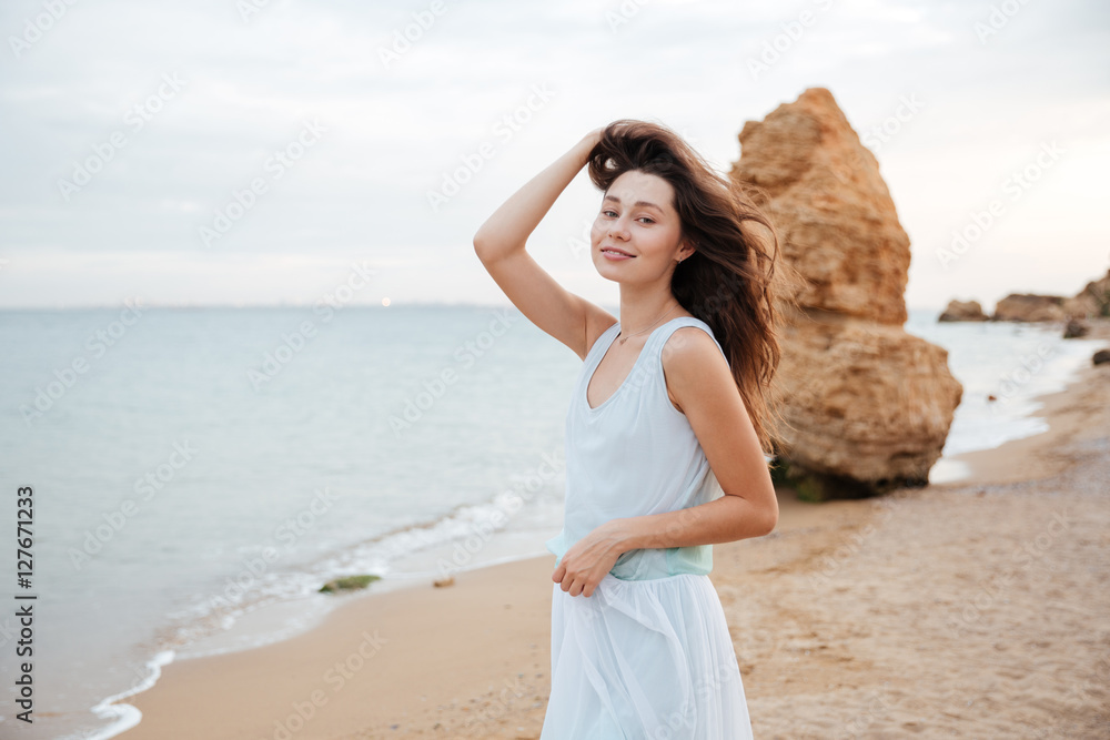 Happy woman in white dress standing on the beach