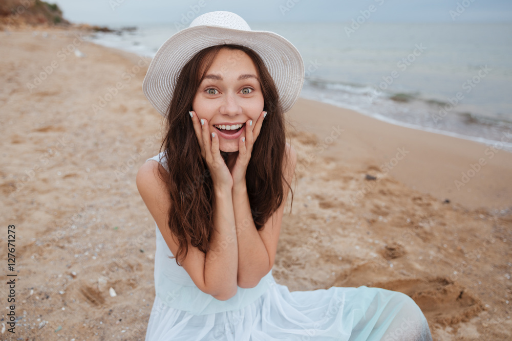 Happy excited young woman sitting on the beach Happy excited young woman sitting on the beach
