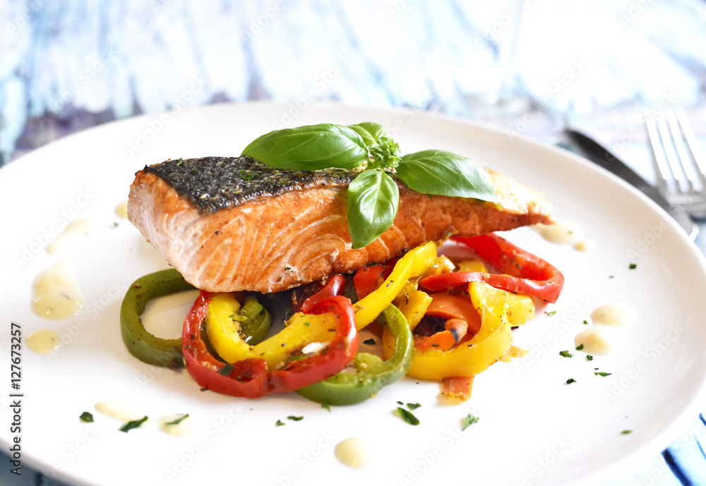 Delicious salmon filet with bell pepper vegetable and decorative basil leaf on a rustic wooden table. Healthy eating. Delicious salmon filet with bell pepper vegetable and decorative basil leaf on a rustic wooden table. Healthy eating.