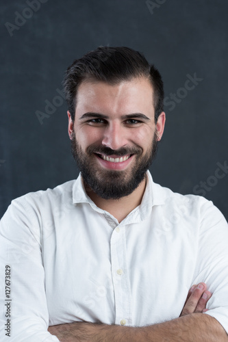 A confident handsome young man standing in front of a dark backg