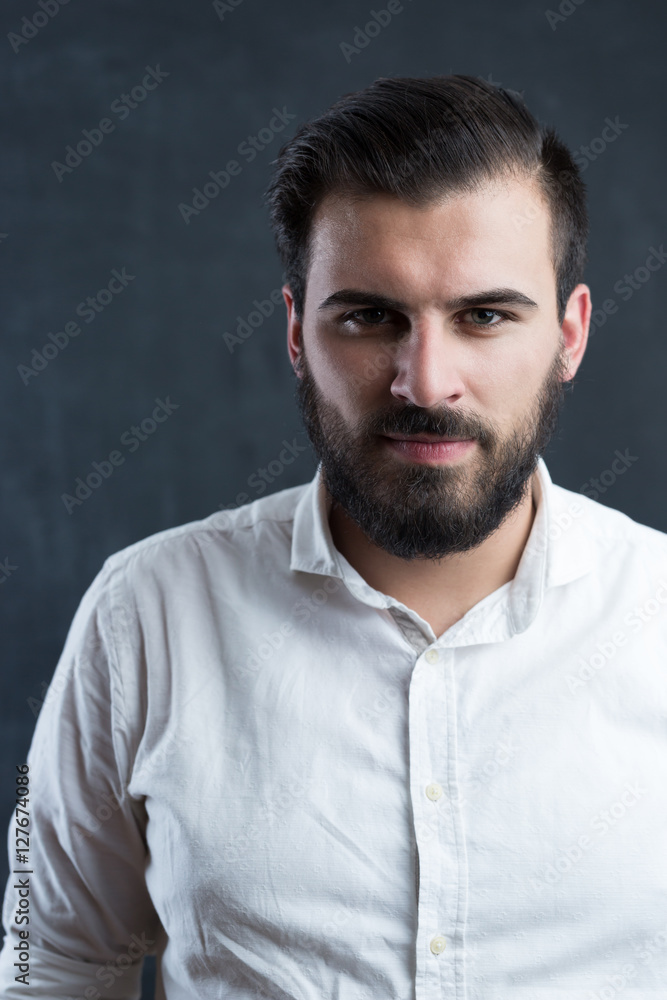 Portrait of a young bearded man against black chalkboard Portrait of a young bearded man against black chalkboard