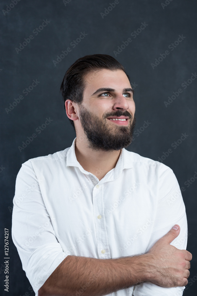 Portrait of a young bearded man thinking against black chalkboa Portrait of a young bearded man thinking against black chalkboa
