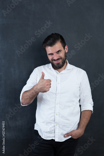 Portrait of a young bearded man smiling against black chalkboar