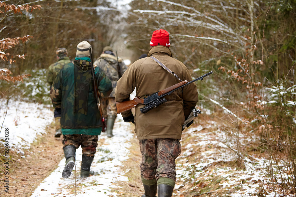 Group of hunters walking in the forest. Winter hunting