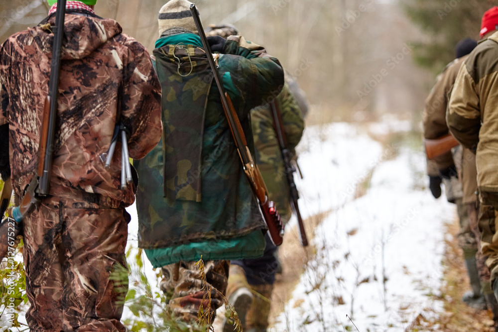 Group of hunters walking in the forest. Winter hunting