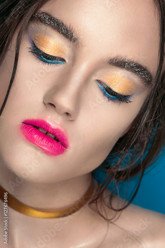 Beauty Girl Portrait with Vivid Makeup. Fashion Woman portrait close up on blue background. Bright Colors. Manicure Make up. Smoky eyes, long eyelashes. Rainbow Colors. Retouched shot