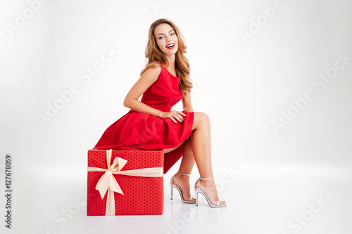 Woman in red dress having fun on big gift box