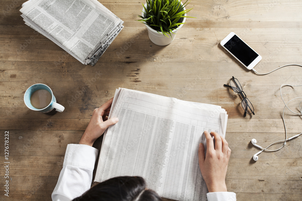 Naklejka premium Reading newspaper on wooden table