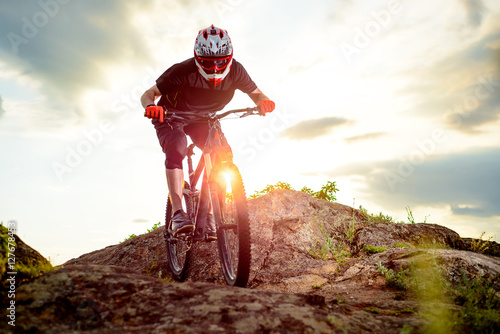 Professional Cyclist Riding the Bike Down Rocky Hill at Sunset. Extreme Sport.