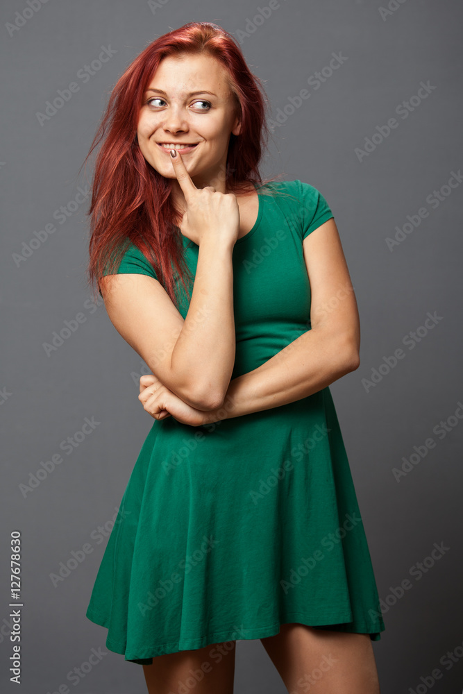 Young ginger girl in a green dress having an idea, gray background Young ginger girl in a green dress having an idea, gray background